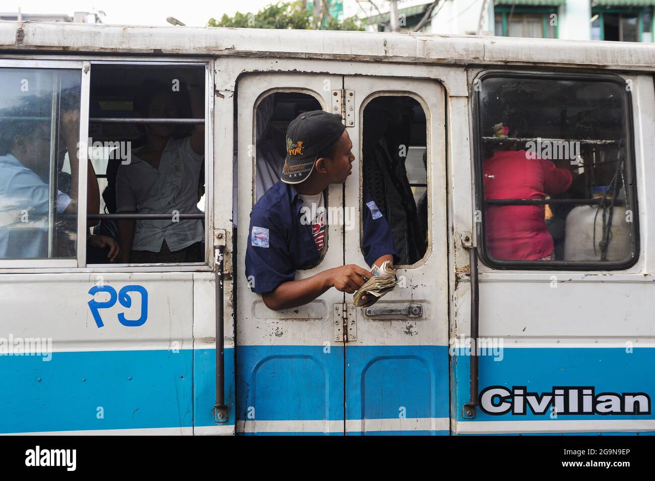 21.02.2014, Yangon, Myanmar, Asia - A bus conductor working in the local transport sector counts the money paid for the fare by the commuters. Stock Photo