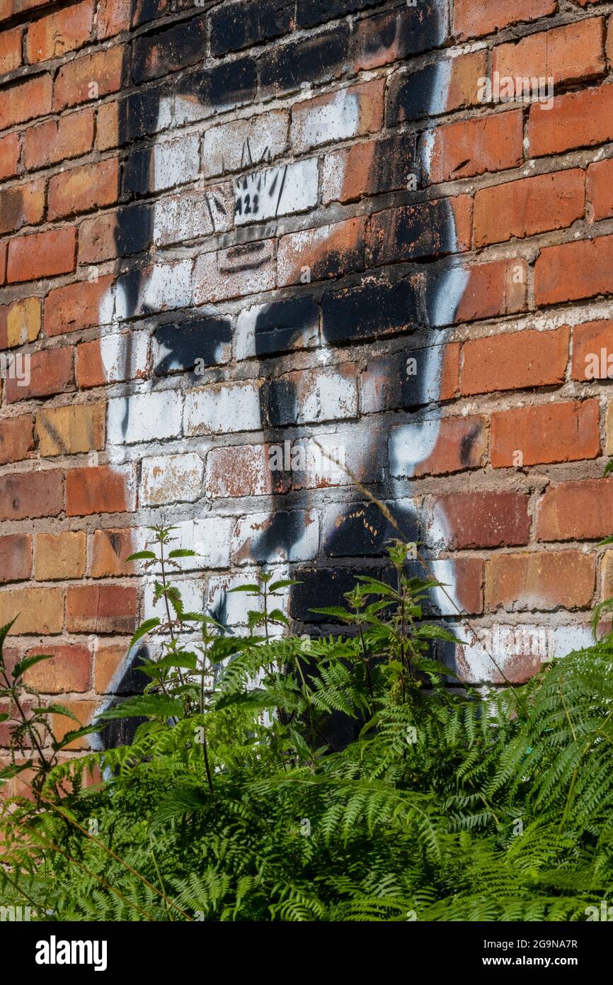 Mans face sprayed onto a wall in street art graffiti style on a red brick building in greater Manchester, uk. Stock Photo