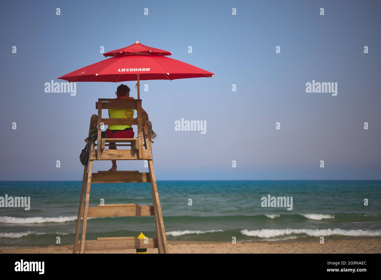 detail of a lifeguard at a lookout point on a beach with the sea and blue sky in the background Stock Photo
