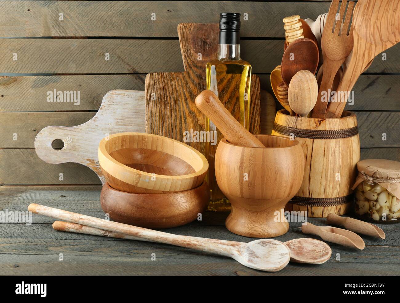 Wooden kitchen utensils with glass bottle of olive oil on wooden planks