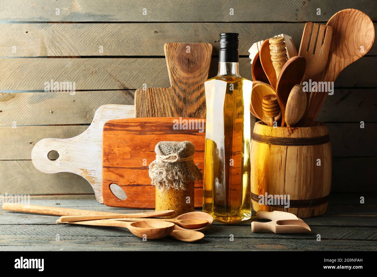 Wooden kitchen utensils with glass bottle of olive oil on wooden planks