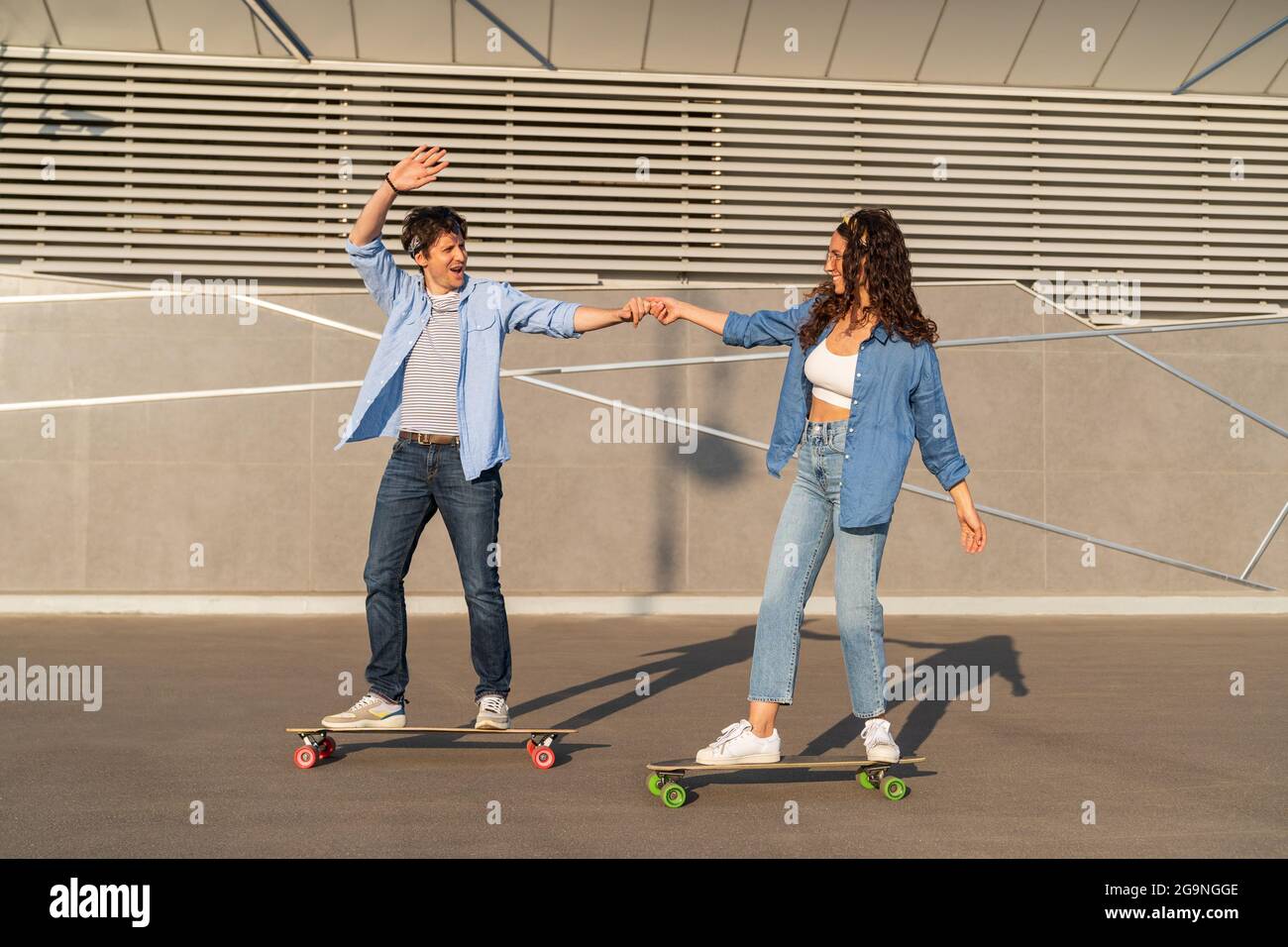 Young couple of hipster skateboarder skate in summer city. Cheerful casual guy and girl on longboard Stock Photo