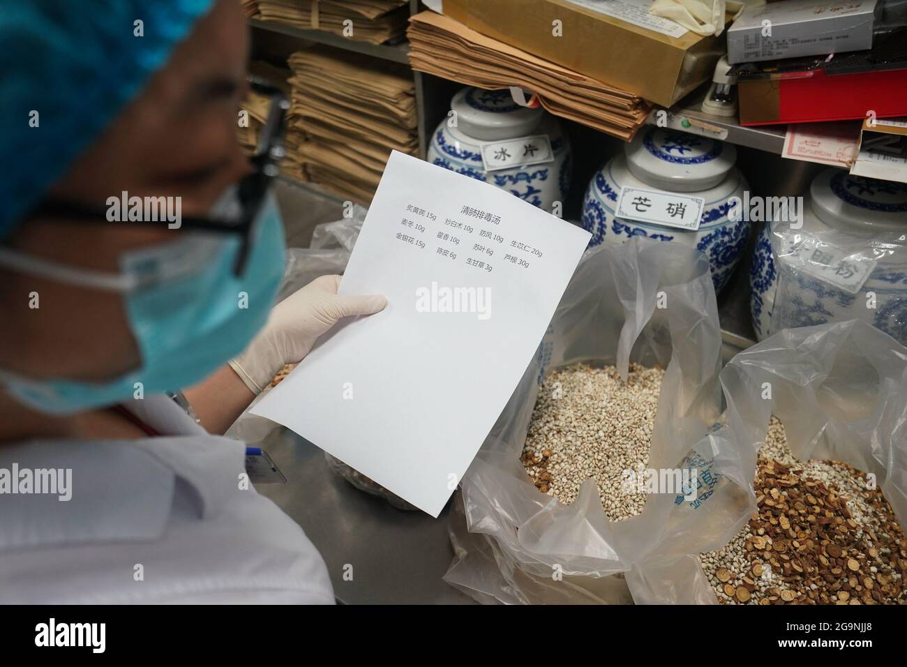 Nanjing, China's Jiangsu Province. 27th July, 2021. A pharmacist of Jiangning Chinese medical hospital prepares ingredients to produce traditional Chinese medicine (TCM) decoctions in Nanjing, capital of east China's Jiangsu Province, July 27, 2021. So far, the hospital has distributed over 15,000 doses of TCM decoctions to help control the recent spike in COVID-19 infections in Nanjing. Credit: Ji Chunpeng/Xinhua/Alamy Live News Stock Photo