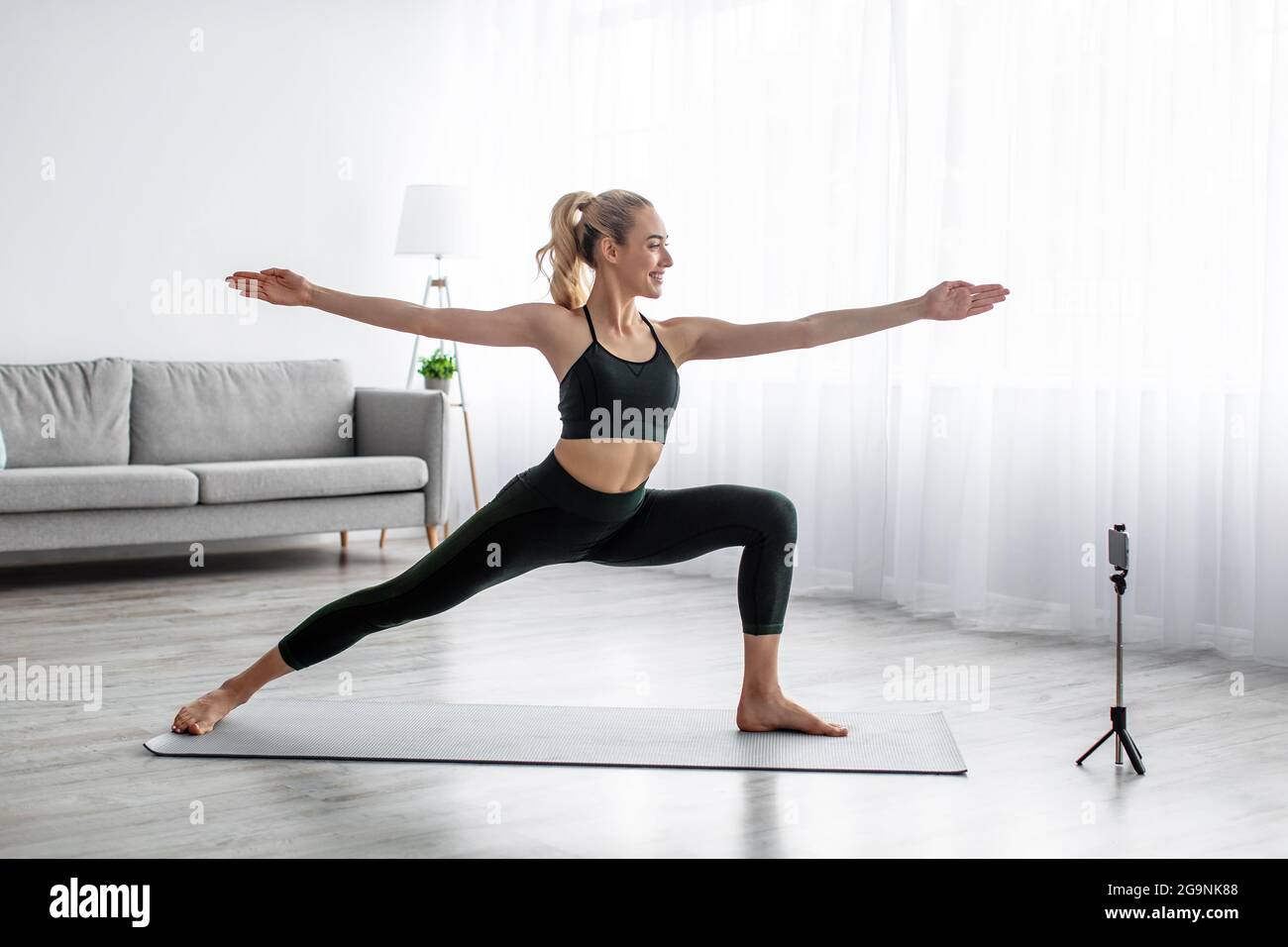 Female coach has virtual class with tech. Healthy and active lifestyle, online home training Stock Photo