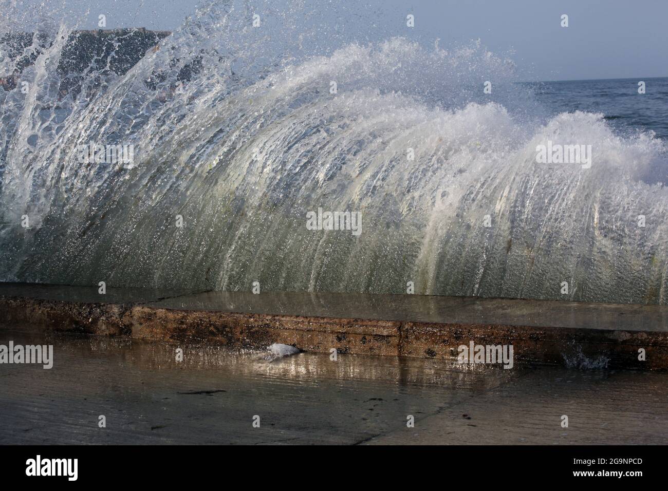 Waves hitting seawall an shooting up to from a curtain of water Stock Photo