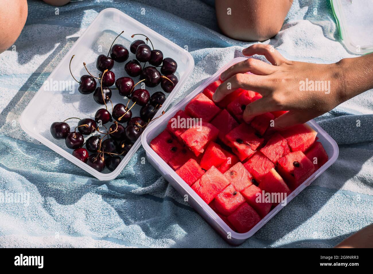 Kid's hands take fruit in a container on the beach Top view Stock Photo