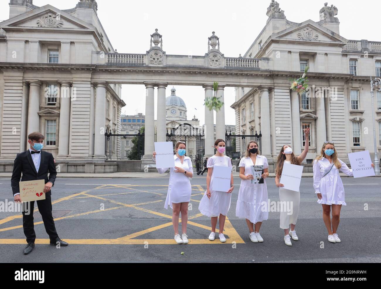 Dublin, Ireland, 27/07/2021. Brides to Be, protest outside Government Buildings in Dublin, Ireland, over restricted guest numbers at weddings due to Covid-19 restrictions. Pictured are “Groom” Tony Hogan with (l to r) Orla Hogan, Ali O'Mara, Brina Cullen, Anna Killeen, Orla O’Huadhaigh as a group of brides-to-be outside Government Buildings to present their health & safety guidelines in a bid to allow their weddings go ahead this year. The centrepiece of the 40 pages of guidelines is to seek to safely raise the guest limit for wedding receptions to 100 guests from August. Photograph: Sam Boal/ Stock Photo