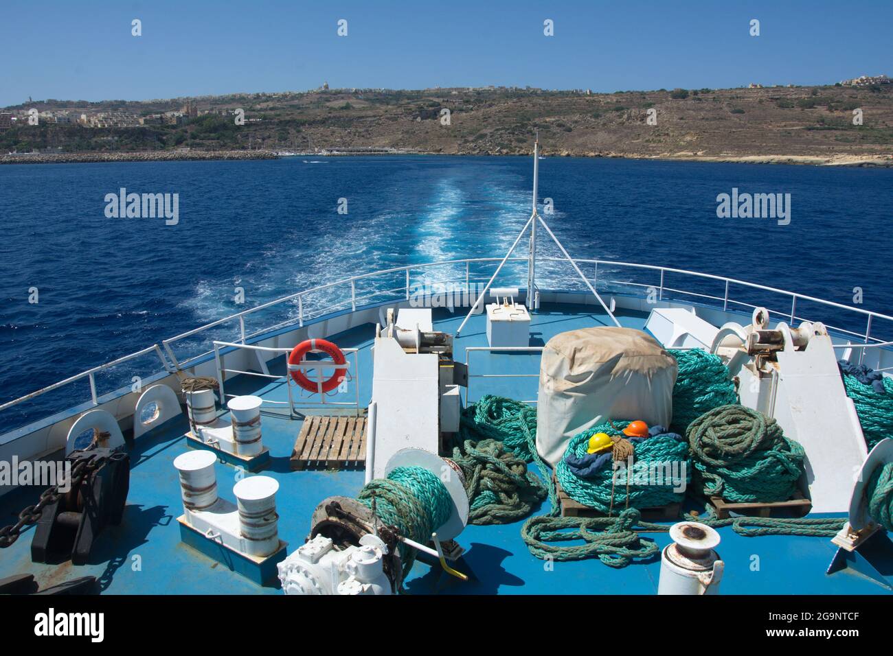 A view from the Gozo Channel Line passenger and vehicle ferry leaving the island of Gozo. Fragment of ferry. Green ropes and construction helmets Stock Photo