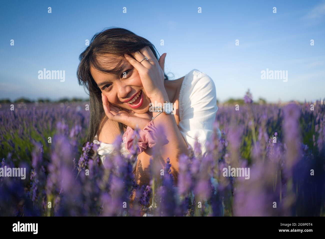 outdoors romantic portrait of young happy and attractive woman in white summer dress enjoying carefree at beautiful lavender flowers field in travel a Stock Photo