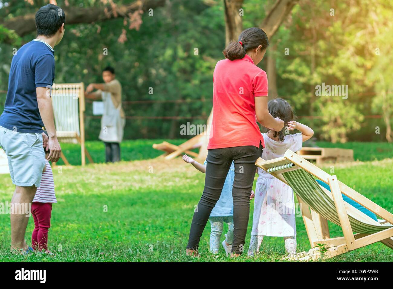 Back view of Asian mother tied up ponytail hair for her daughter on lawn in  green garden. Lovely moment of family. Happy family spending time together  Stock Photo - Alamy