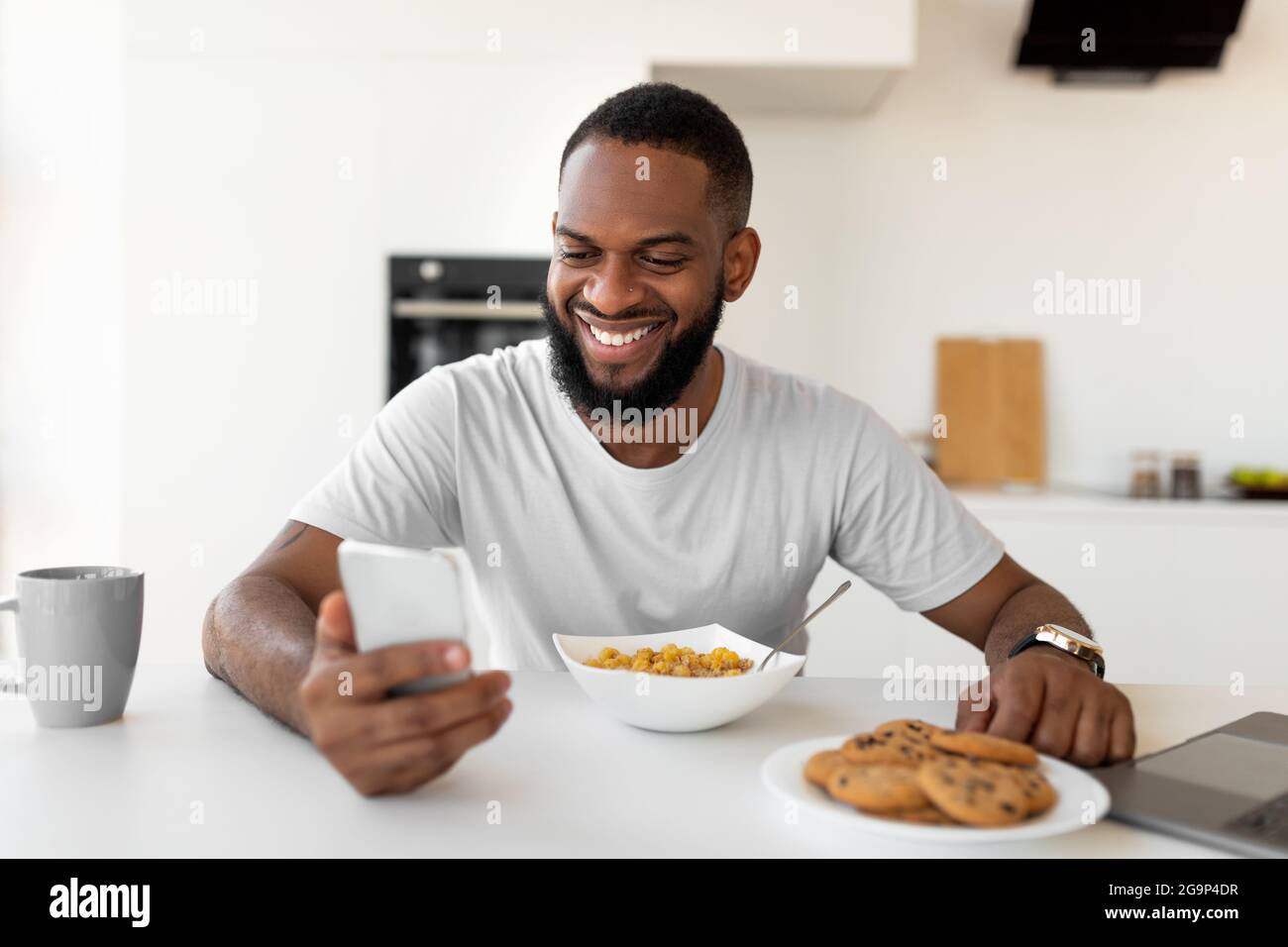 Black man texting on his smartphone having breakfast at home Stock ...