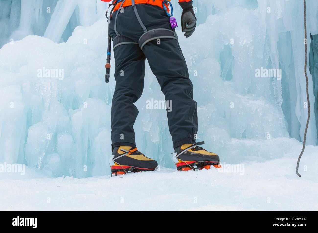 Male ice climber tying a rope to his harness, preparing for a climb