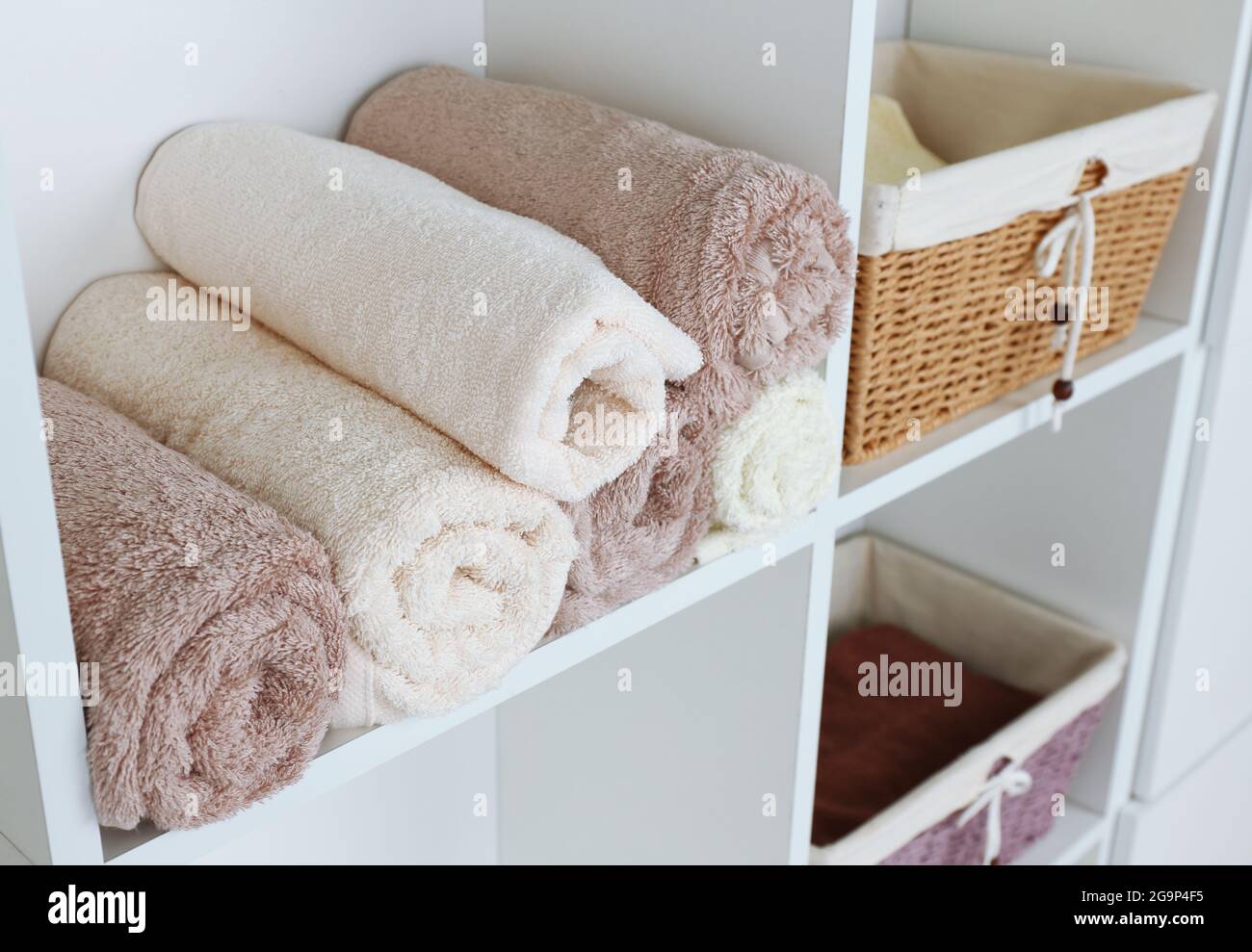 Rolled towels with wicker basket on shelf of rack background Stock Photo Alamy