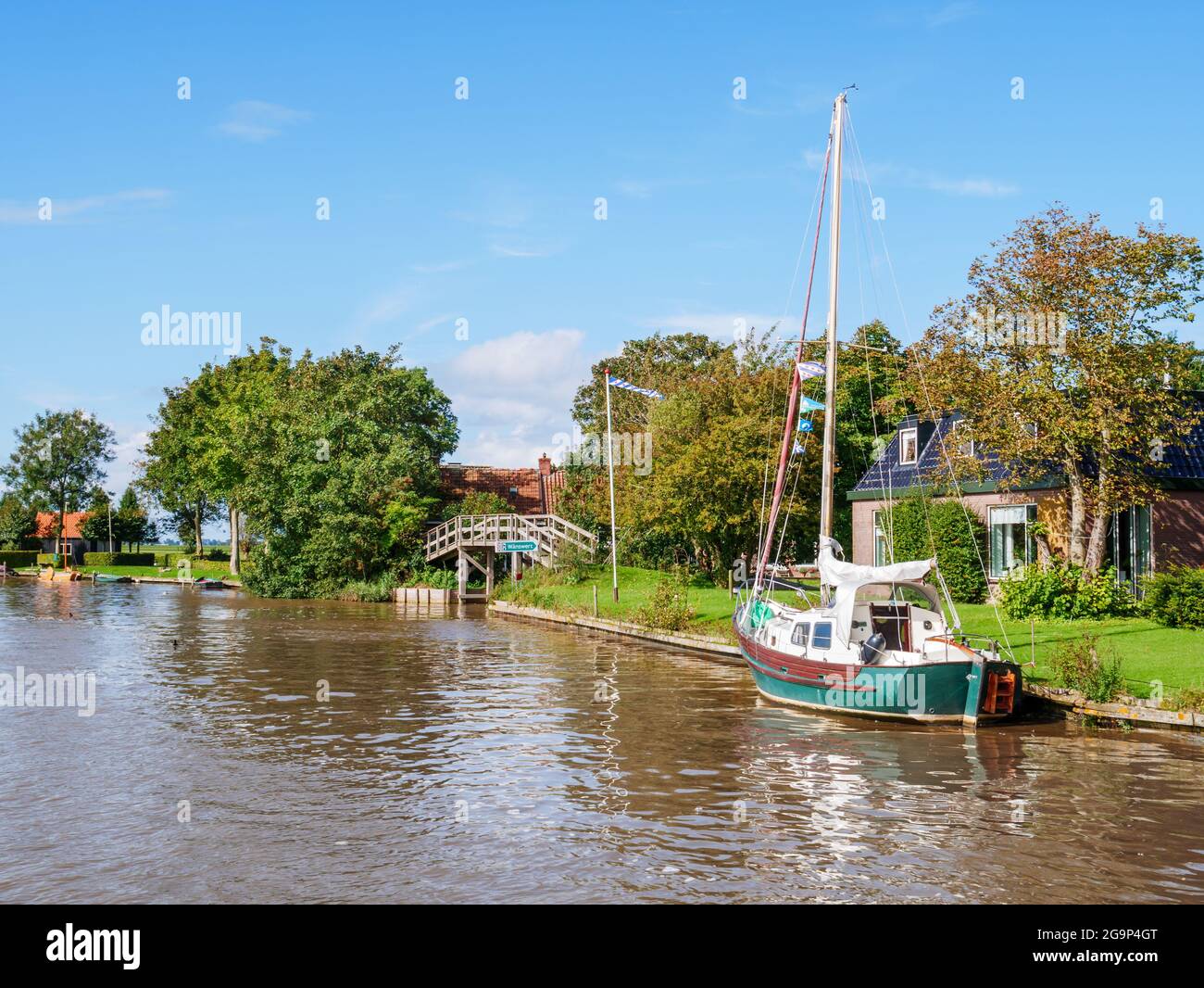 Dokkumer Ee canal with sailboat and bridge in old town of Birdaard in Friesland, Netherlands Stock Photo