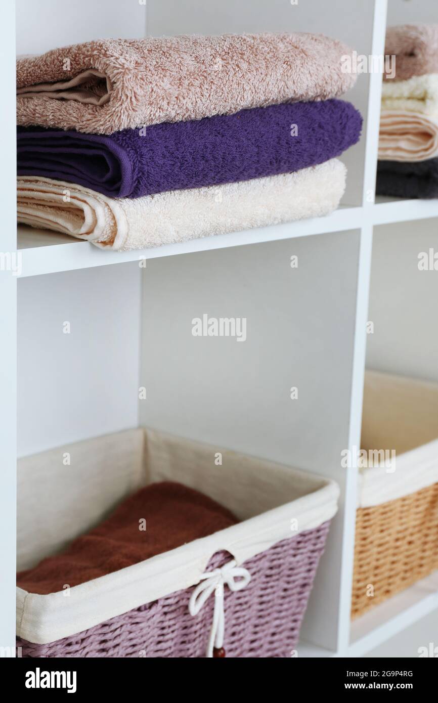 Colorful towels with wicker baskets on shelf of rack background Stock