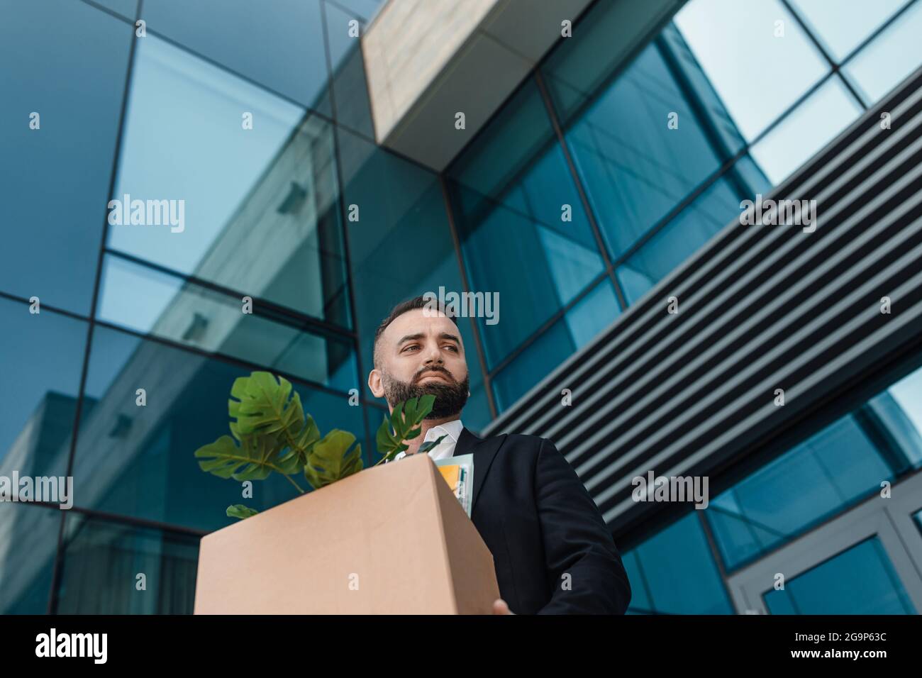 Upset mature businessman walking outdoors with box of stuff leaving business center, free space Stock Photo