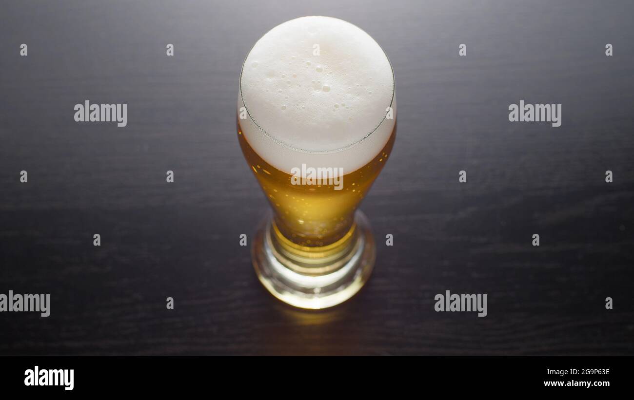 Beer in glass, view from above. Half pint of frothy fresh lager beer on table. Top view. Stock Photo