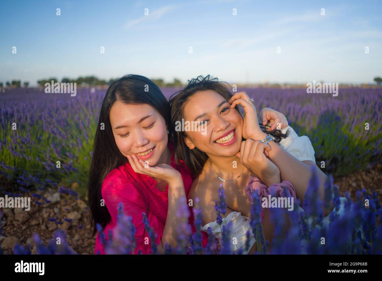 young happy and beautiful Asian korean woman playing on lavender flowers field with her hispanic girlfriend enjoying sweet holidays together relaxed a Stock Photo