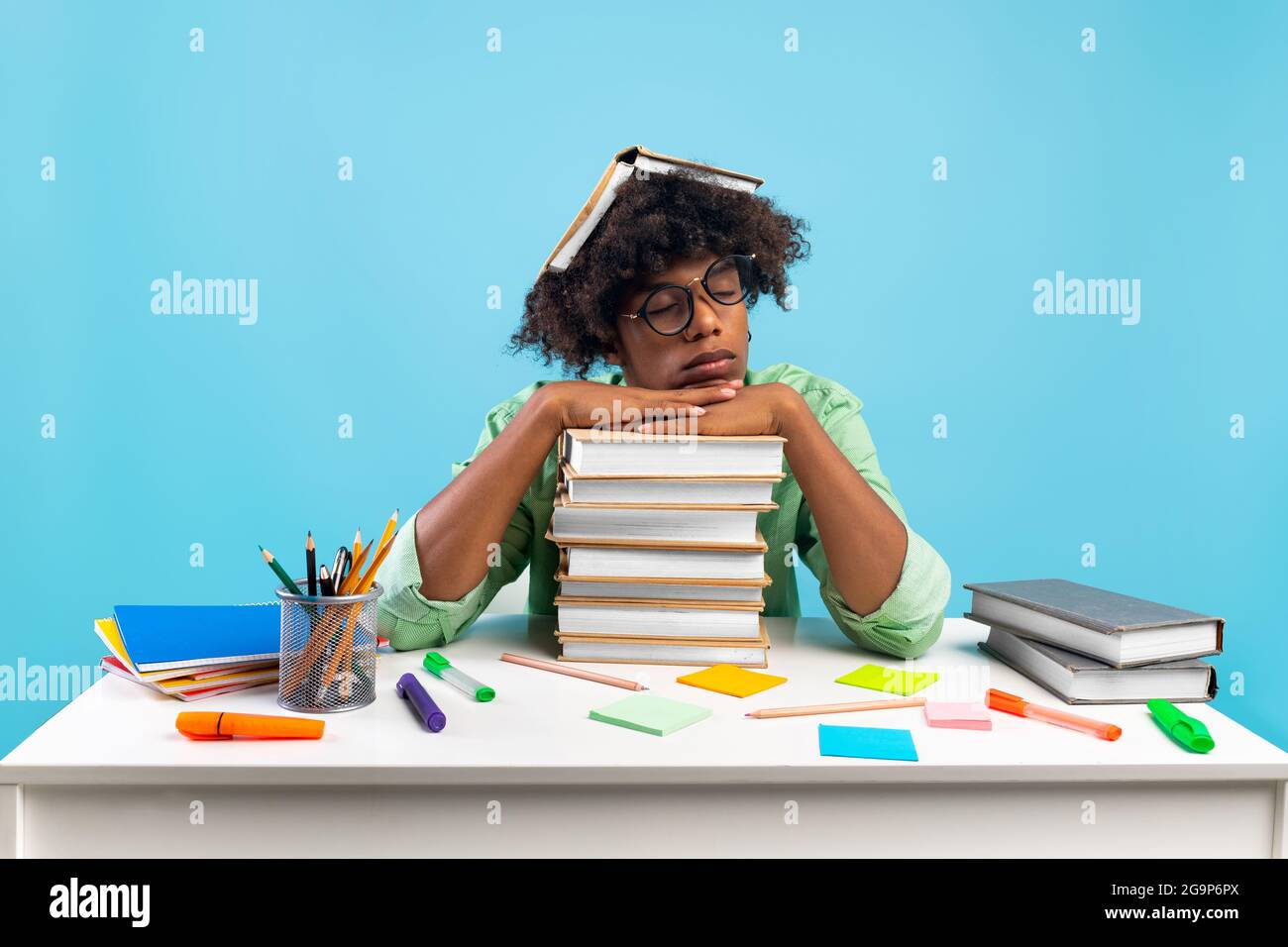 Tired african american student guy having nap on books, being exhausted during preparing for exams, blue background Stock Photo