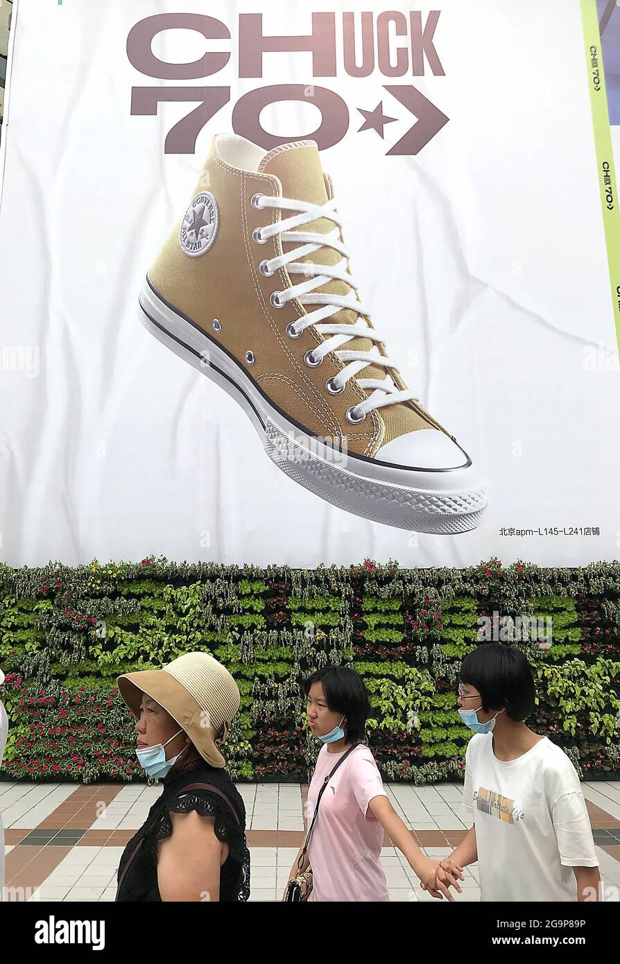 Beijing, China. 27th July, 2021. Chinese walk past a new Converse showroom  in downtown Beijing, on Tuesday, July 27, 2021. Converse, as with many  popular U.S. athletic clothing stores, has targeted China