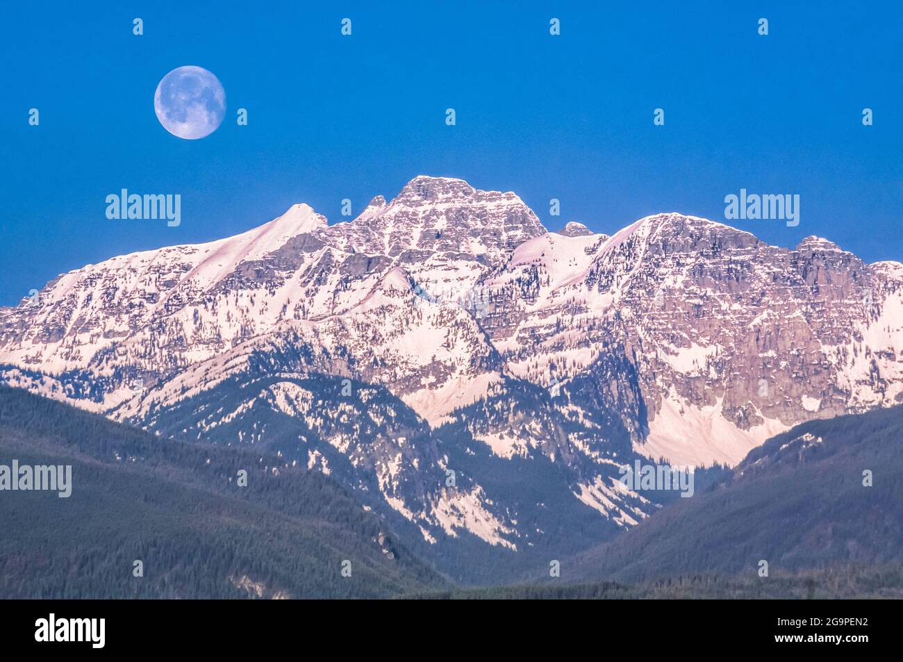 moon over peaks of the mission range above elk creek valley near condon, montana Stock Photo