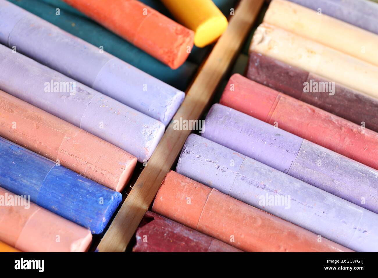 A close up photograph of a box of colorful used chalk pastels