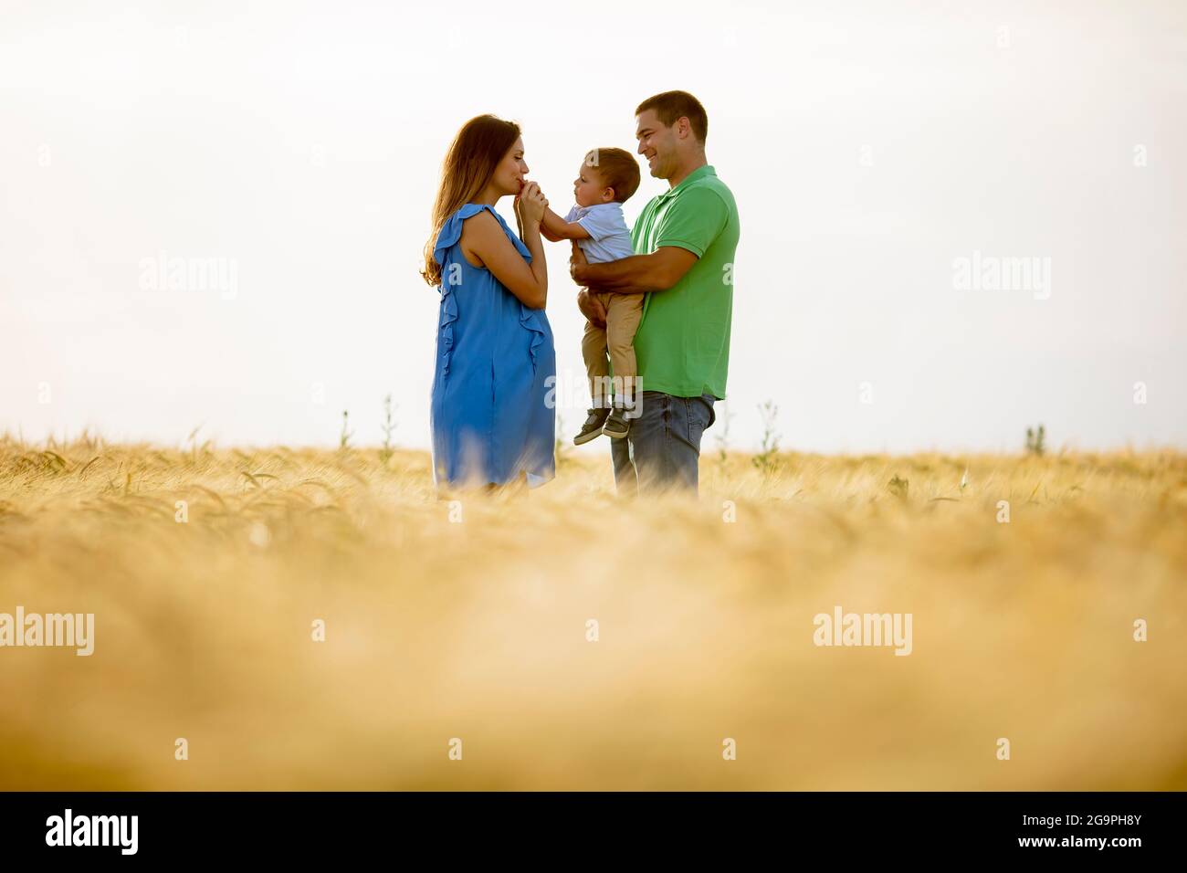 Young family with cute little boy having fun outdoors in the summer field Stock Photo