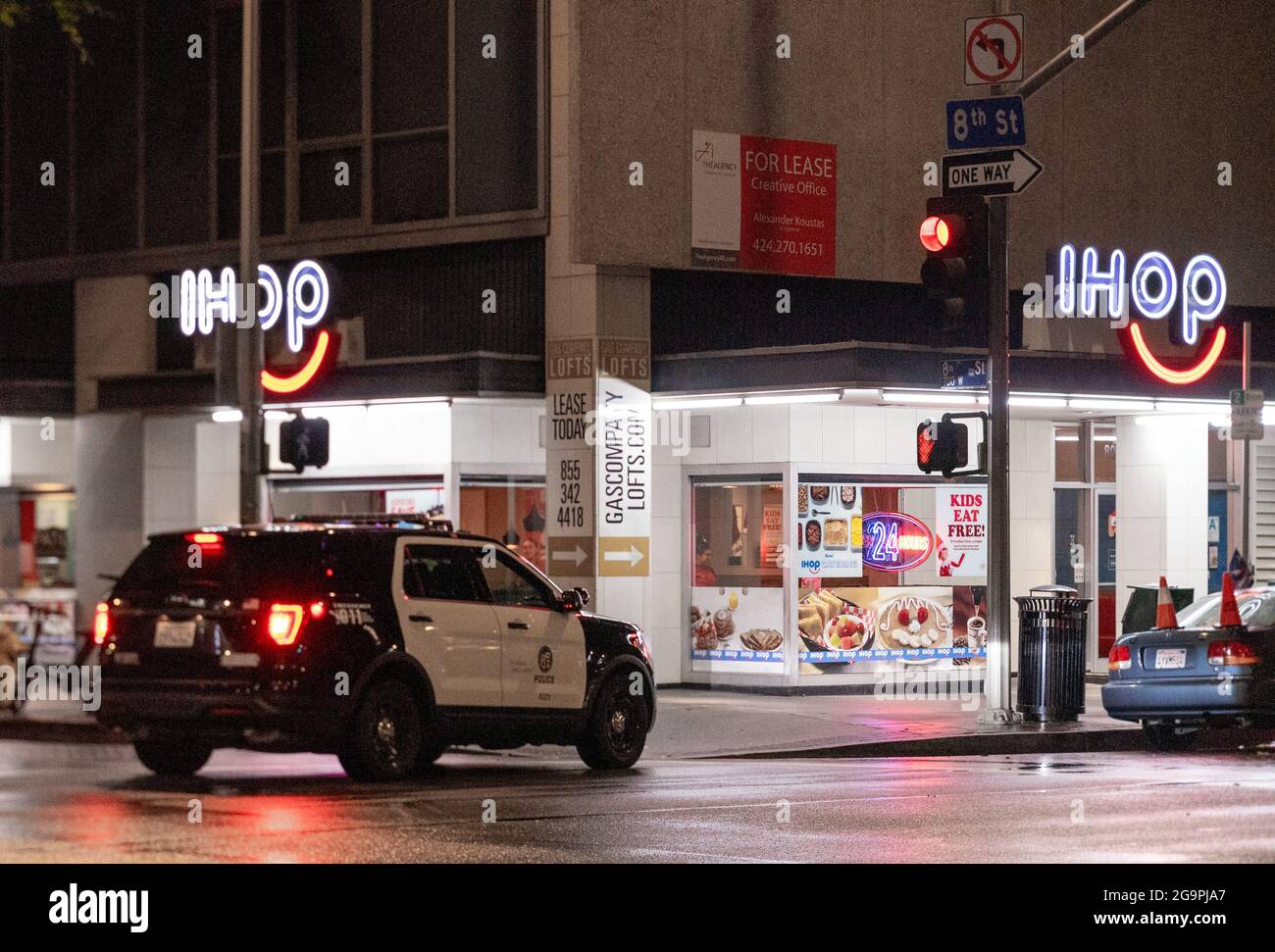 Police car parked near IHOP restaurant, lit up at night, corner of 8th street & Flower str, Downtown Los Angeles, California, United States Stock Photo