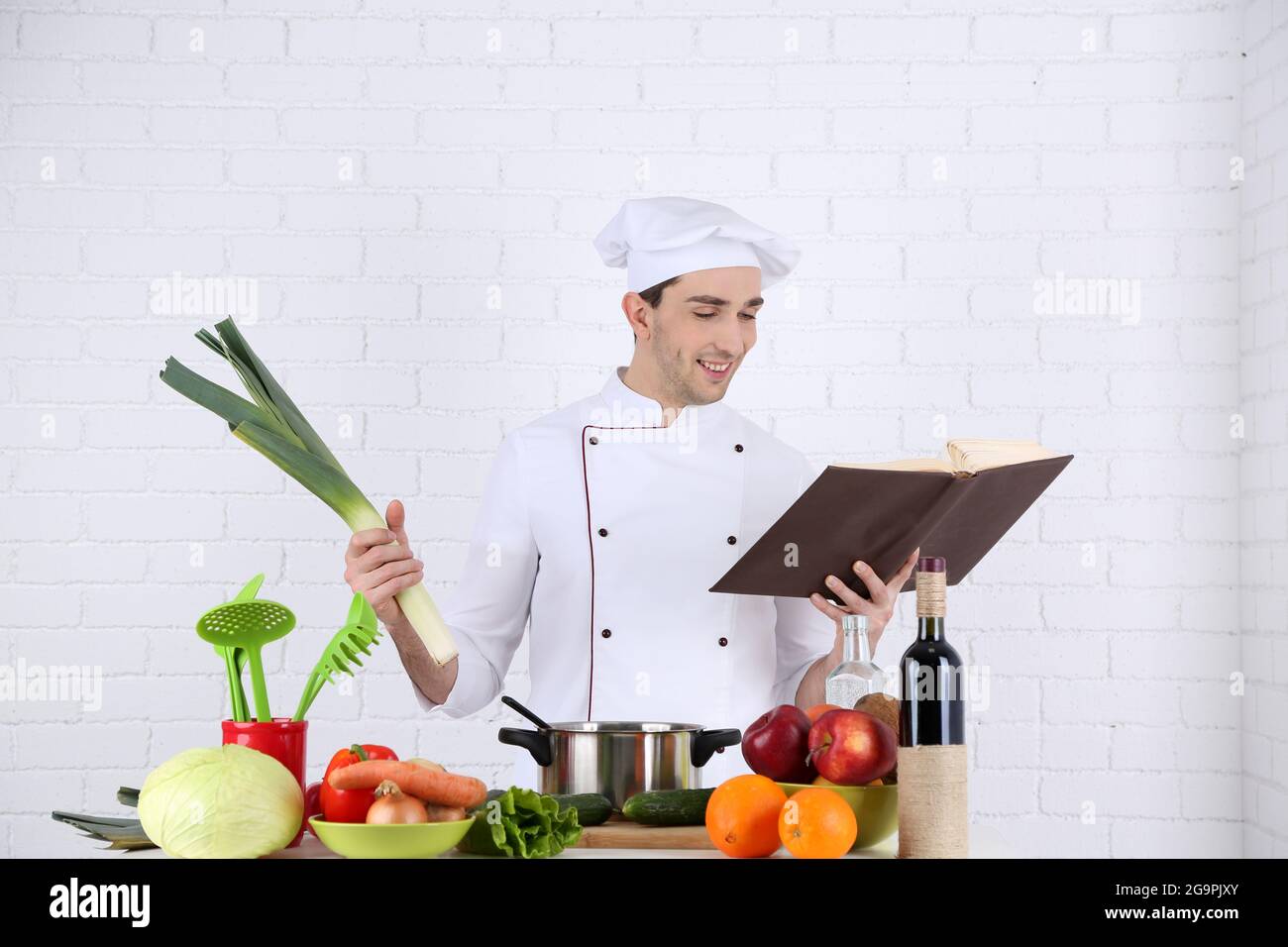 Chef at table with different products and utensil in kitchen on white ...