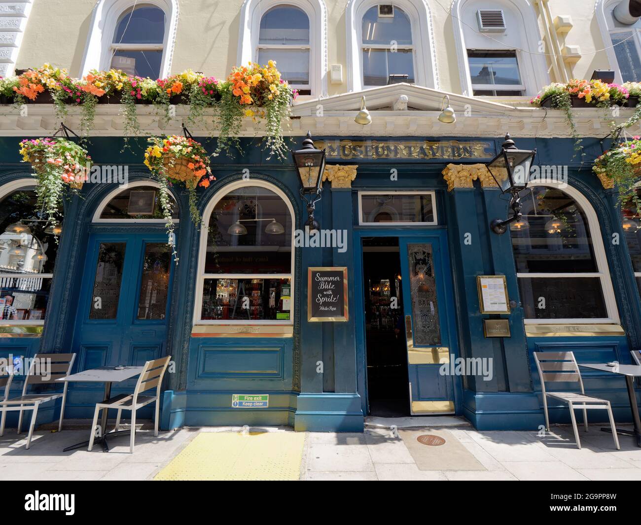 London, Greater London, England, July 17 2021: Entrance to the The Greene King Museum Tavern in Bloomsbury with hanging flower baskets and table and c Stock Photo