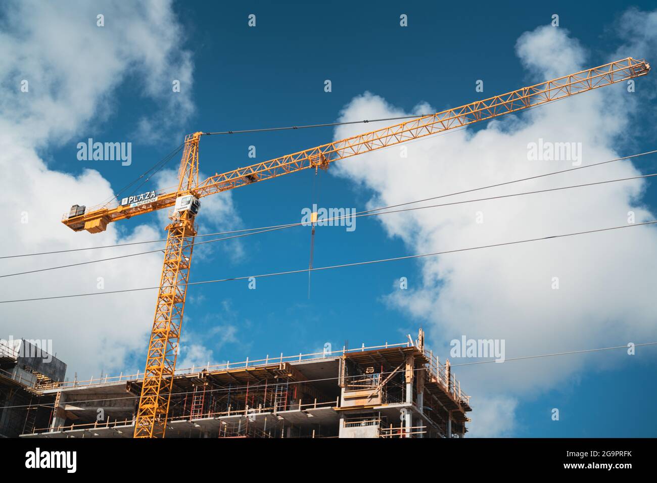 Low angle shot of a tower crane at a construction site against a cloudy ...
