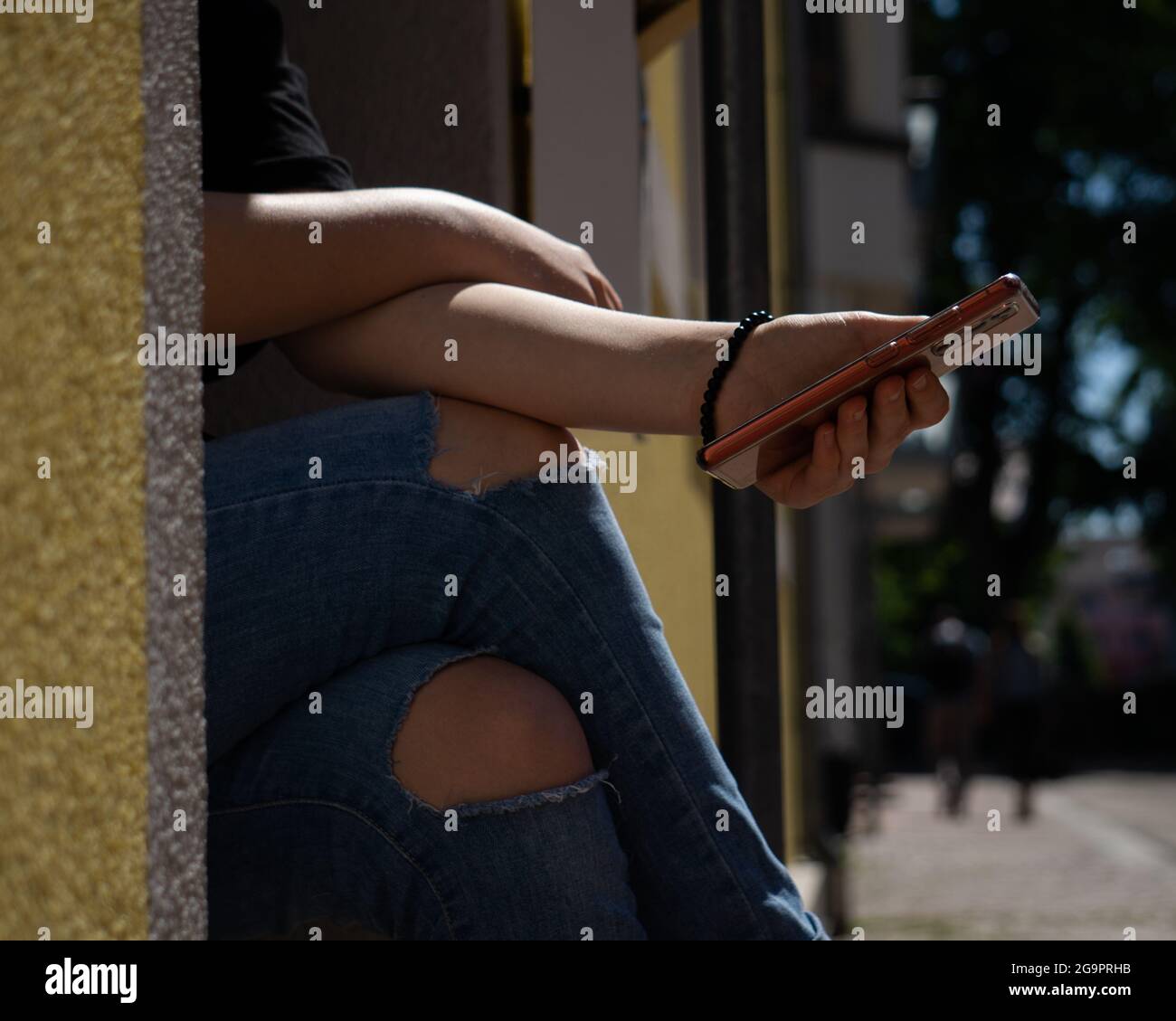 Hand scrolling through her phone while sitting outdoors Stock Photo - Alamy