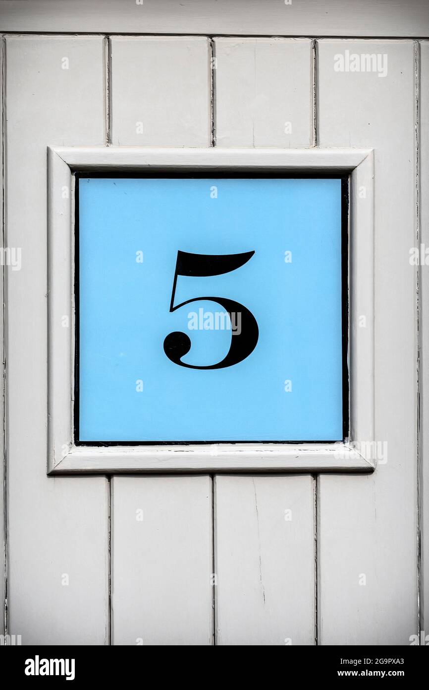 Number five framed on blue background on wooden door Stock Photo