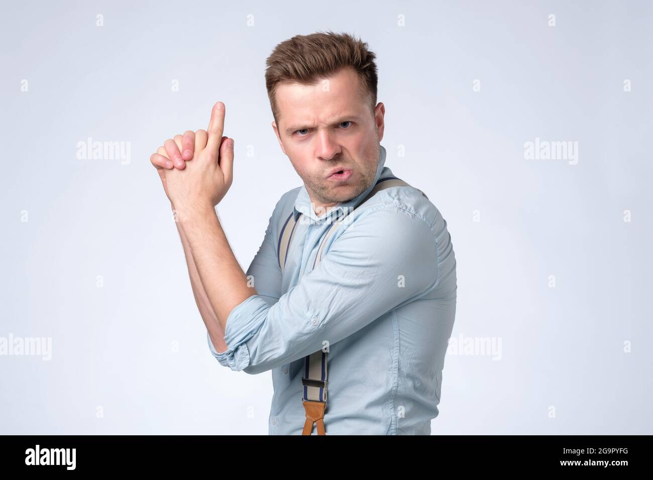 Caucasian young man shouting with gun hand gesture. Stock Photo