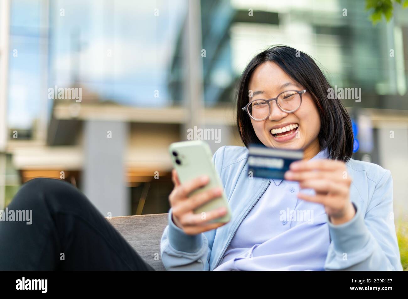 Happy young woman using cell phone to make mobile transaction Stock Photo