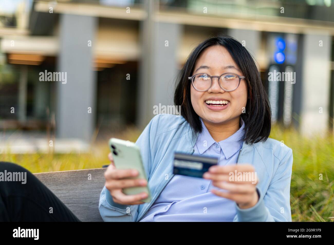 Young woman looking at camera holding credit card and cell phone Stock Photo