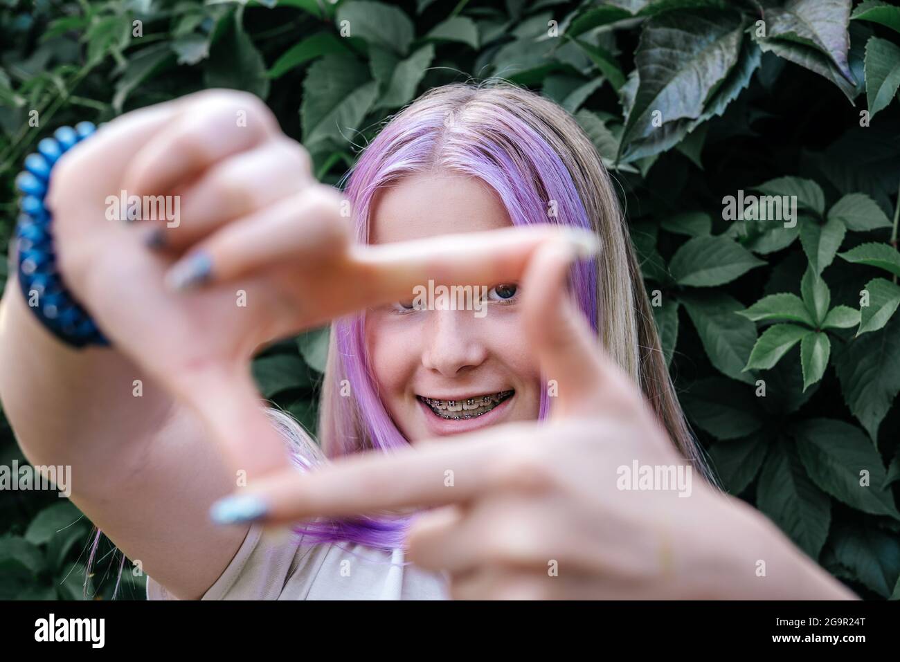 Happy girl wearing dental braces on dark green vine background, cute