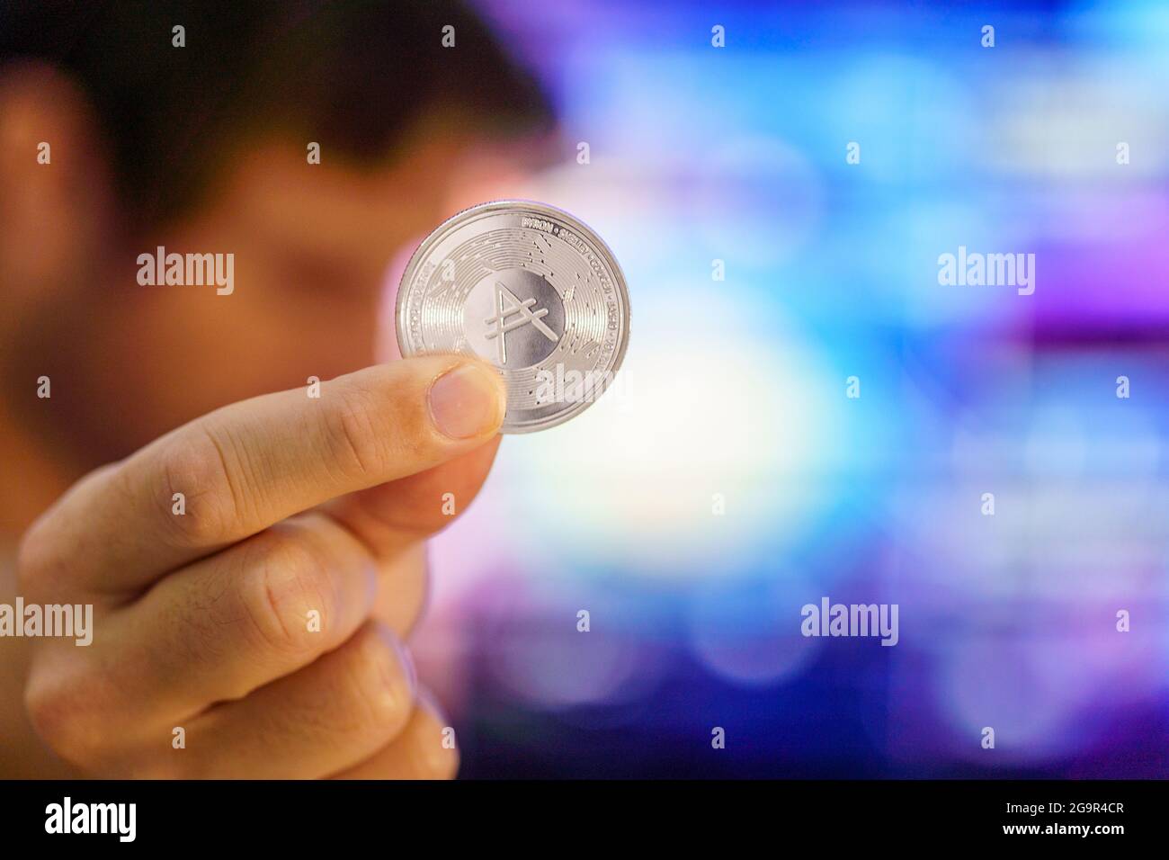Men holding a Cardano coin. Logo ADA coin, top crypto coins based on the ethereum  cryptocurrency. Cardano logo in a silver coin holding from a trader Stock  Photo - Alamy