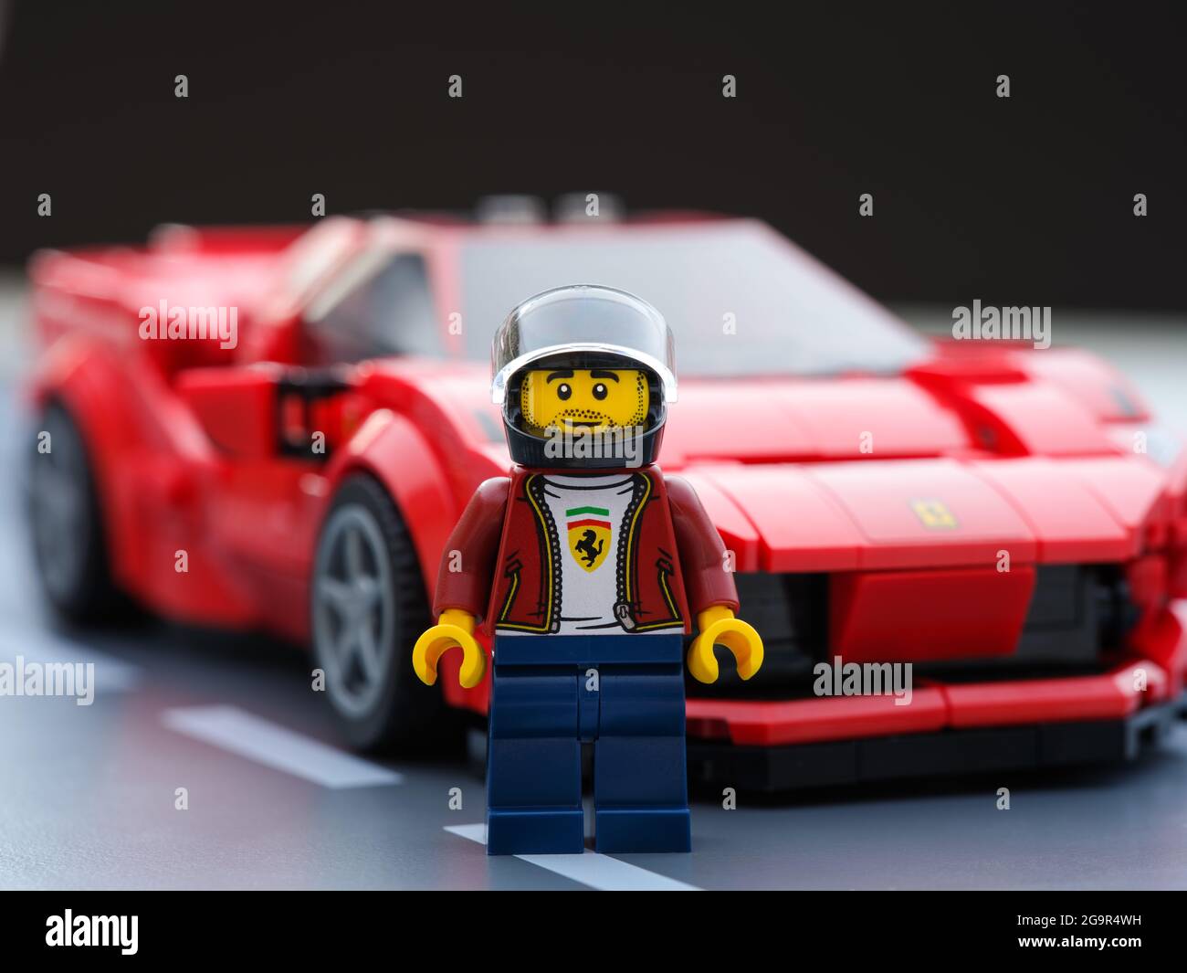 Tambov, Russian Federation - July 09, 2021 Lego driver minifigure and his car Ferrari F8 Tributo by LEGO Speed Champions on road baseplate. Black bsck Stock Photo