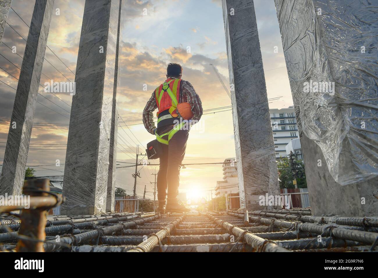 Construction worker wearing safety work at high uniform on scaffolding at construction site on during sunset Stock Photo