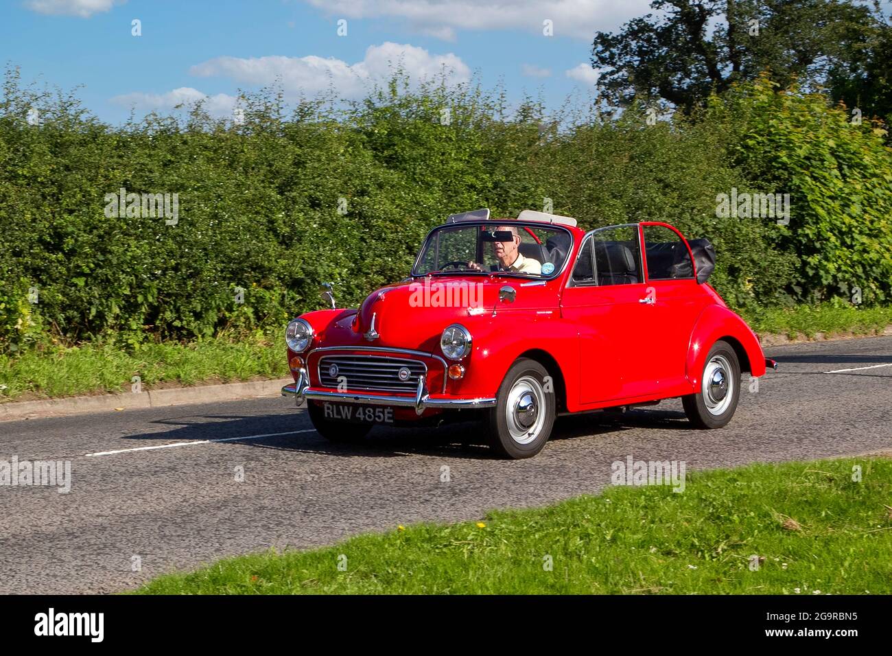1960s Red Morris Minor 1000 vehicle en-route to Capesthorne Hall classic July car show, Cheshire, UK Stock Photo