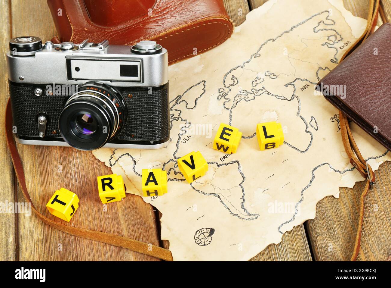 Retro camera on world map with word Travel on wooden table background Stock Photo