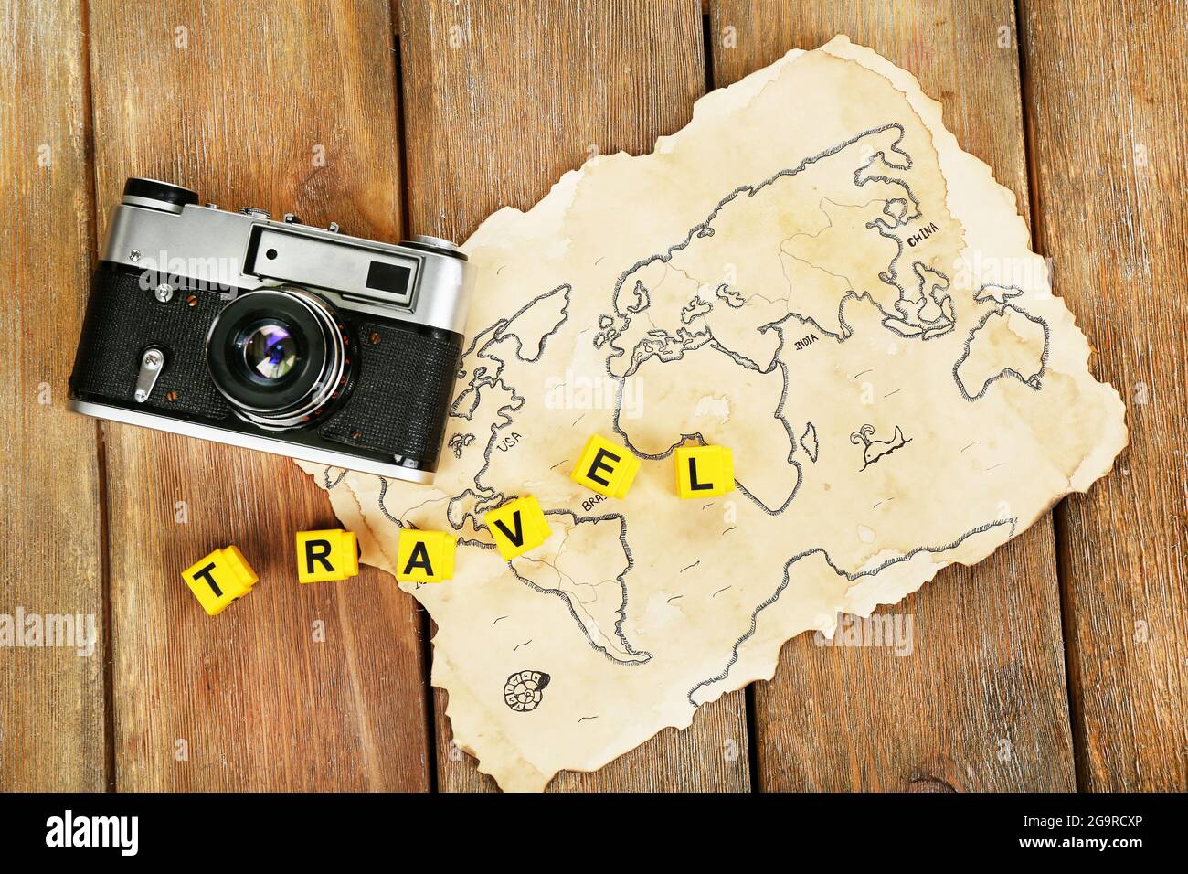 Retro camera on world map with word Travel on wooden table background Stock Photo