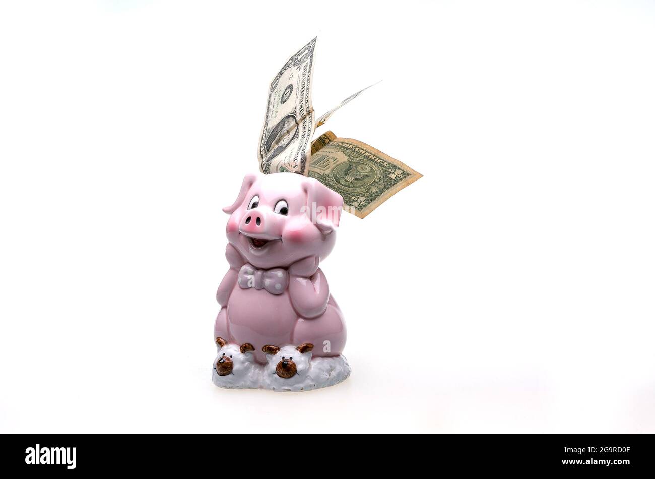 Pink piggy bank in the form of a cute pig and dollar bills. The composition is isolated on a white background. Stock Photo