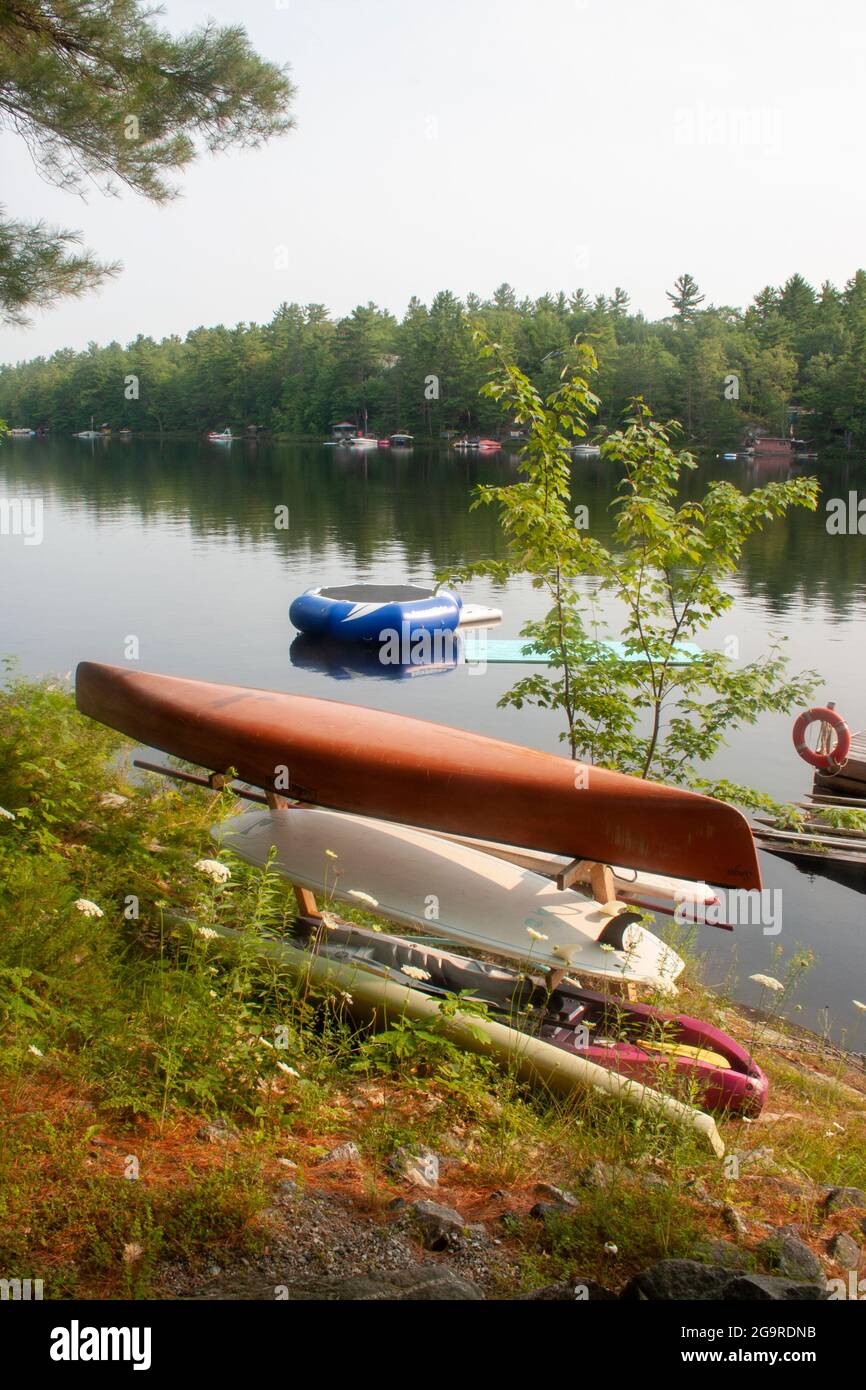 A canoe sits along the shoreline of a Muskoka, Ontario lake Stock Photo