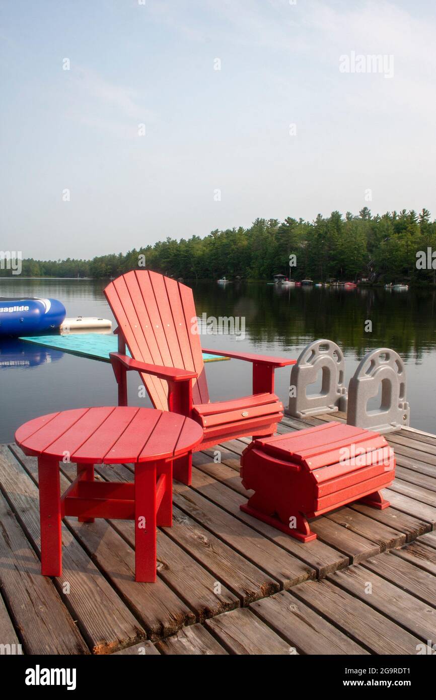 A chair and table set on the dock of a cottage in Muskoka, Ontario Stock Photo