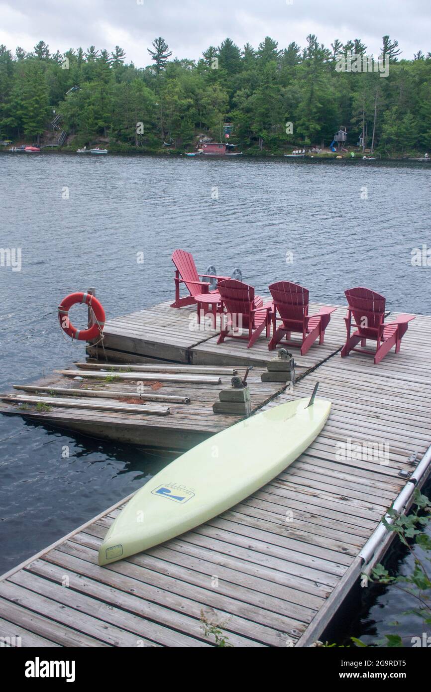A paddle board and chairs on the dock of a lake in Muskoka, Ontario Stock Photo