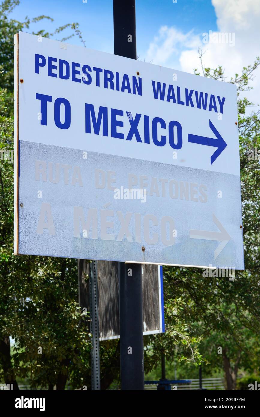 A white sign with blue lettering and arrow reads 'Pedestrian Walkway to Mexico', at the border of US-Mexico in Douglas, AZ Stock Photo