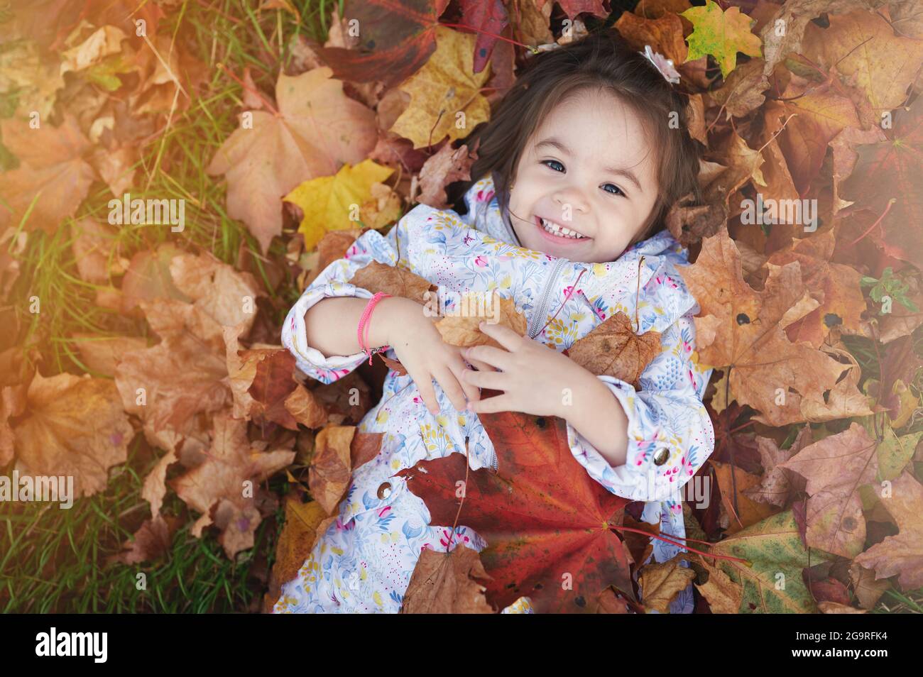 Pretty happy smiling kid girl portrait around yellow autumn leaf background Stock Photo