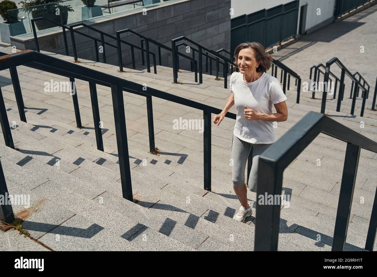 Smiling aged slim female going jogging outdoors Stock Photo - Alamy